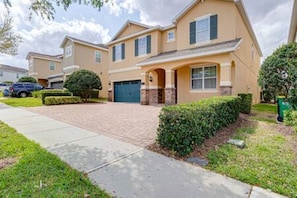 A two-story residential building with a brick driveway, a garage, and a well-maintained lawn. - ECR641 - Stunning Dream Vacation+Theater @Encore (Kissimmee)
