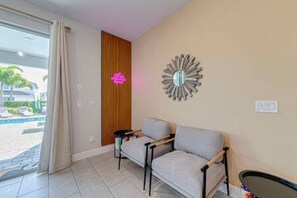 A modern living room with a sofa, a coffee table, and a decorative mirror on the wall. - ECR313 - Resort Style Mansion + Gyn/Spa/Theater! (Kissimmee)