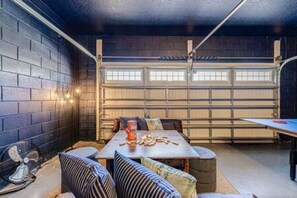 A garage with a table and chairs, a fan, and a window with blinds. - ECR313 - Resort Style Mansion + Gyn/Spa/Theater! (Kissimmee)