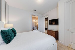 A hotel room with a bed, a dresser, a television, and a bathroom visible through an open door. - ECR7617 - Bright Villa 8B | Theater + Game Room! (Kissimmee)