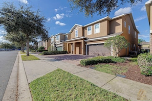 A residential area with townhouses, a clear sky, and a well-maintained lawn. - ECR7617 - Bright Villa 8B | Theater + Game Room! (Kissimmee)