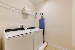 A laundry room with two stacked washers and dryers, a shelf with folded towels, and a blue towel rack. - ECR7713 - Disney Family Friendly Vacation @Encore! (Kissimmee)