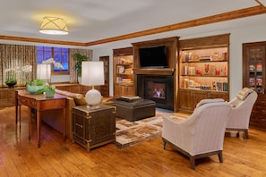 A cozy living room with a fireplace, a television, and a bookshelf. - St Regis Aspen Residence Club, Super Lux 2 Bedroom, 2.5 Bath Residence (Aspen)