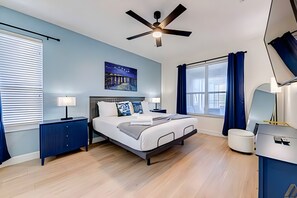 A modern bedroom with a bed, bedside tables, a ceiling fan, a window with curtains, and a wall-mounted TV. - EIR2706 - Lakefront Resort Home, 7B, 8 min to Disney (Kissimmee)