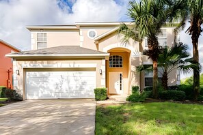 A two-story house with a garage, a covered entryway, and a well-maintained lawn. - EIR2706 - Lakefront Resort Home, 7B, 8 min to Disney (Kissimmee)