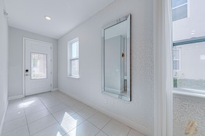 A hallway with a door, a window, and a mirror on the wall. - ECR456 - Luxury Resort Design Home @ Encore! (Kissimmee)