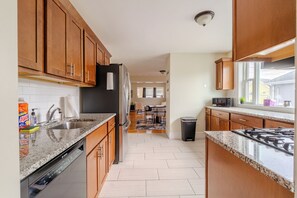 A modern kitchen with wooden cabinets, stainless steel appliances, and a granite countertop.