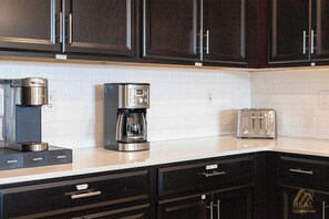 A kitchen with dark cabinets, a coffee maker, a toaster, and a white tiled backsplash. - CG9327 - 3B Resort Access Vacation Retreat (Davenport)