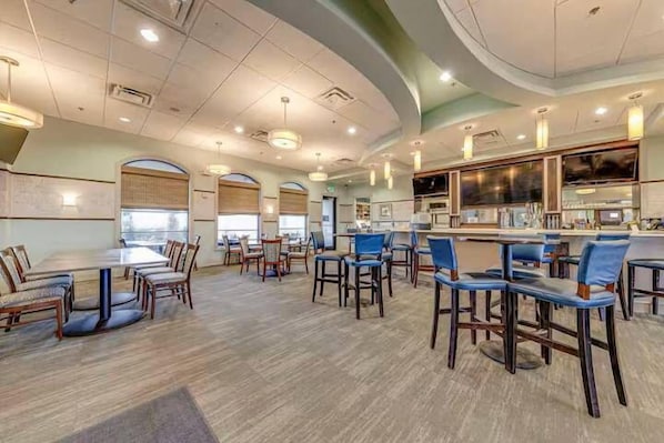 A spacious dining area with multiple tables and chairs, a bar area, and a large window providing natural light. - Resort Access Vacation Retreat! | CG9327 (Davenport)