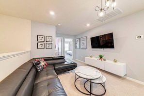 A living room with a black leather sofa, a round coffee table, and a white console table against the wall. - WIR3753 - Family Resort Access Vacation @Disney (Davenport)