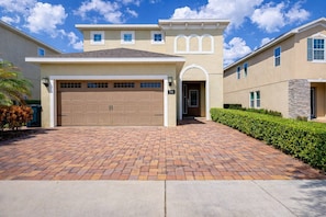A modern two-story house with a garage, a well-maintained driveway, and a landscaped front yard. - ECR7407 - Disney Vacation Retreat @Encore (Kissimmee)