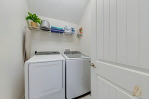 A laundry room with two front-loading washing machines, a shelf with folded clothes and a potted plant. - ECR7783 - 4B Family Friendly Vacation @Encore! (Kissimmee)