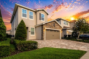A two-story house with a garage, a stone facade, and a well-maintained lawn. - ECR409 - Home 10 minutes from Disney @Encore (Kissimmee)