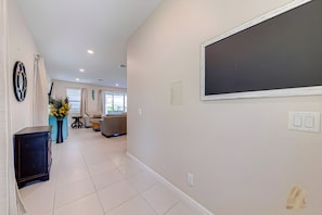 A spacious living area with a large window, a sofa, and a decorative mirror. - ECR409 - Home 10 minutes from Disney @Encore (Kissimmee)