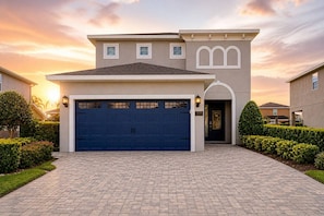 A modern two-story house with a large garage, a well-maintained driveway, and a landscaped front yard. - ECR7739 - Resort Style Home 10 min from Disney! (Kissimmee)