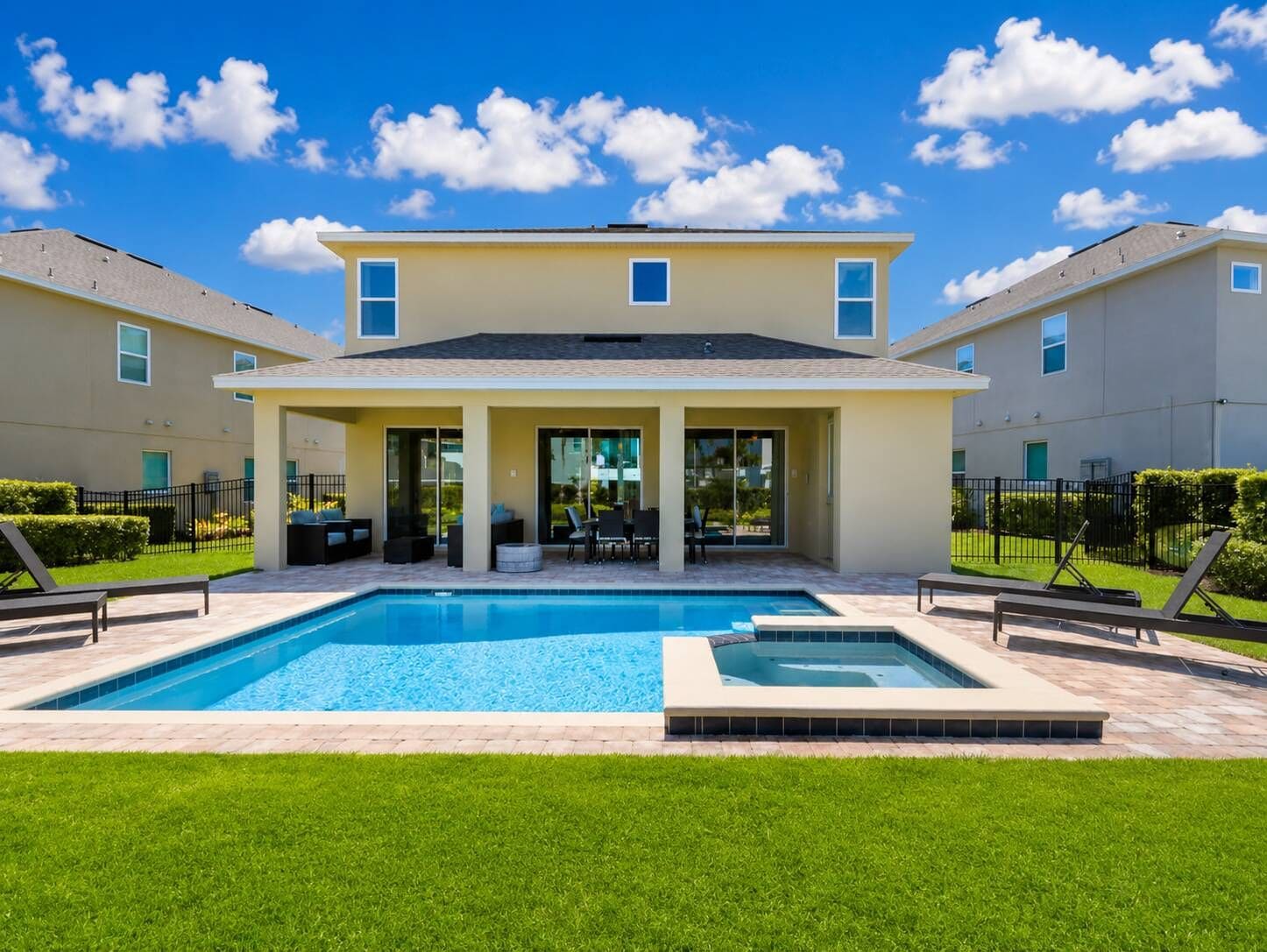 A residential building with a swimming pool, outdoor seating, and a well-maintained lawn.