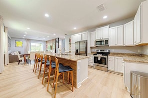A modern kitchen with white cabinets, a granite countertop, and stainless steel appliances. - Soccer Legend Zico’s Official Orlando Home | 8BR (Kissimmee)