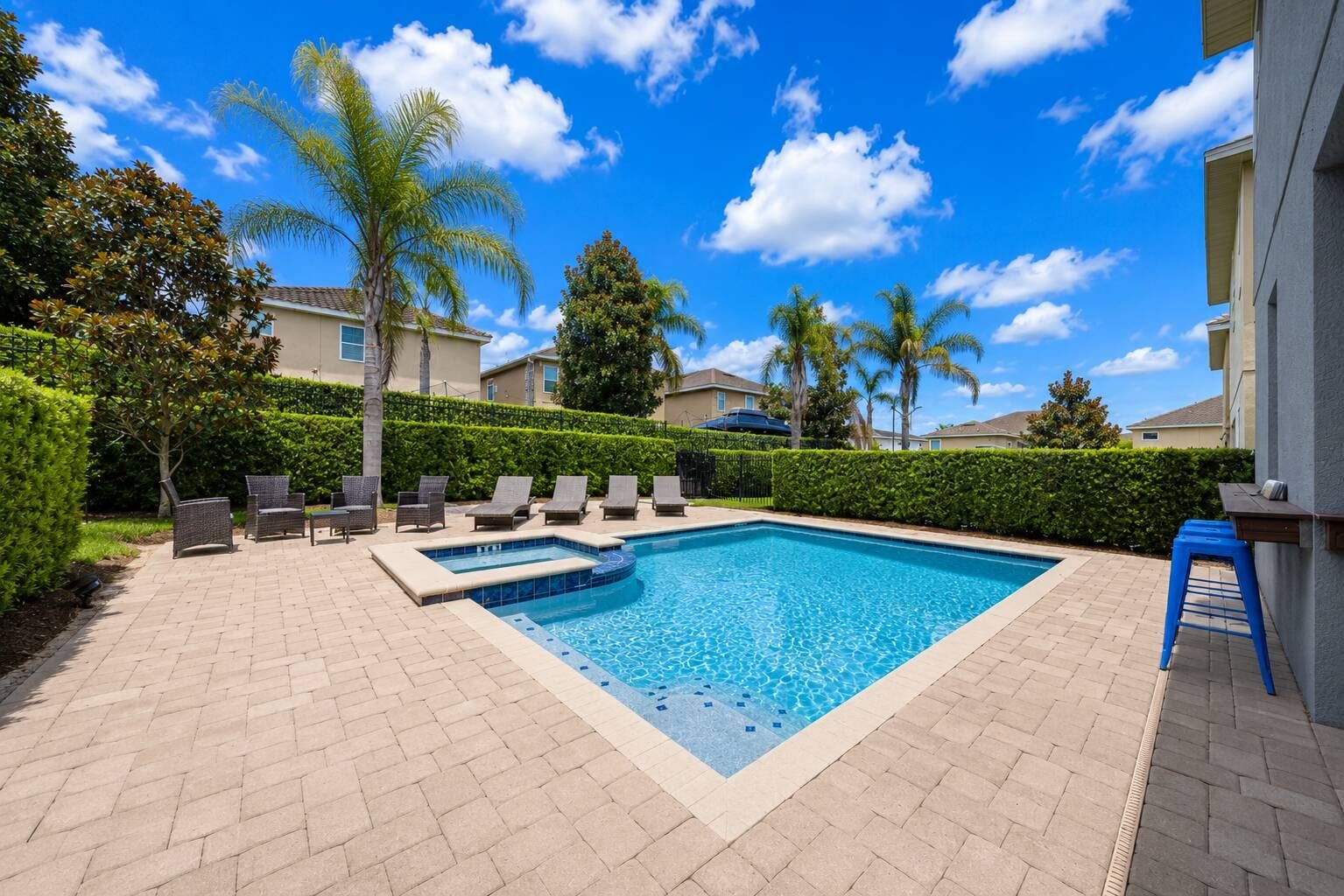 A rectangular swimming pool with a tiled edge, surrounded by a brick patio.