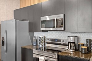 A modern kitchen with stainless steel appliances, including a refrigerator, microwave, oven, and coffee maker. - ECR3385 Only 13 Minutes from Disney | Pool & GYN (Kissimmee)