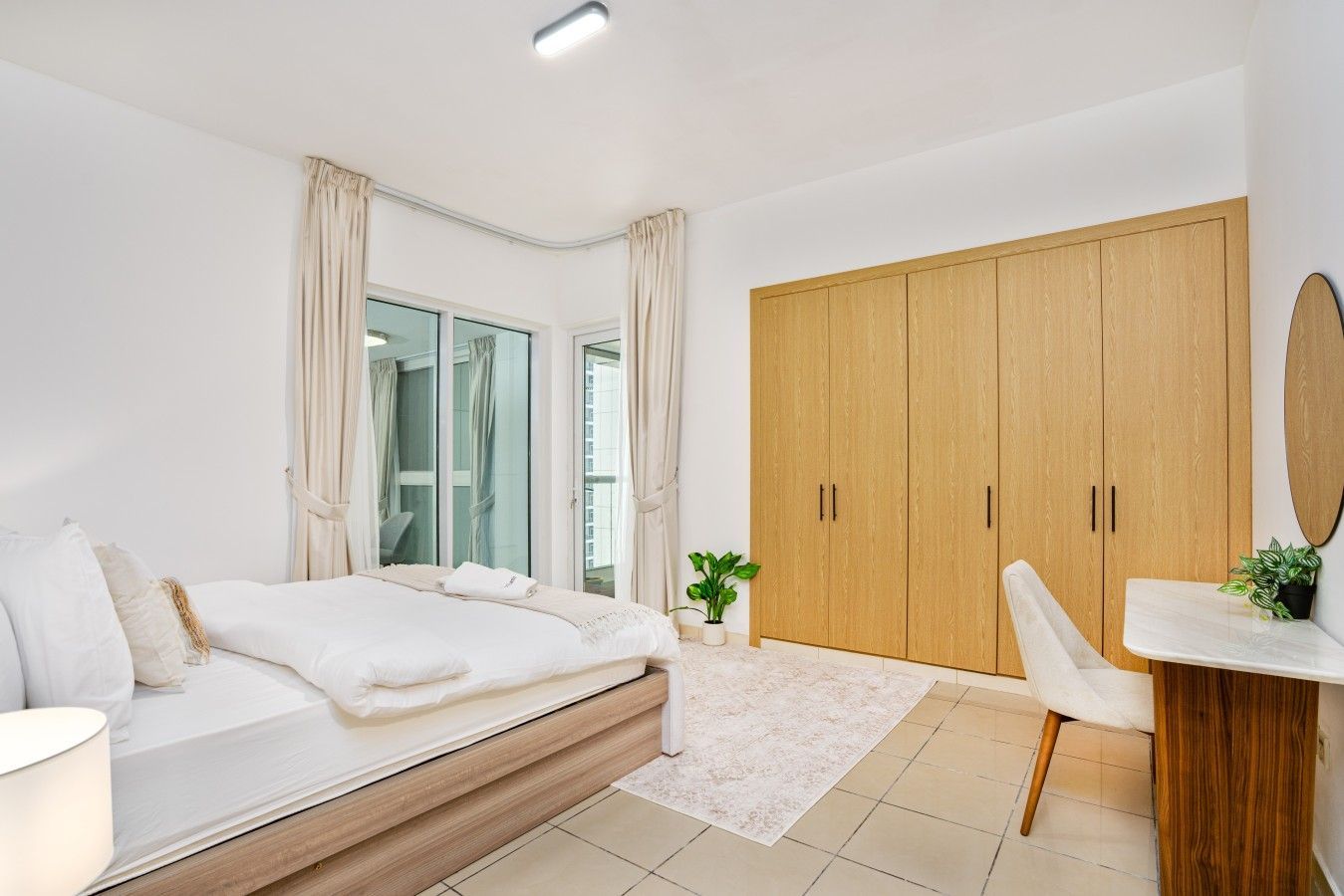Une chambre à coucher avec un lit, un bureau, une armoire et une plante en pot.