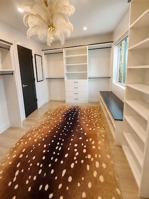 Un dressing sans porte avec des étagères ouvertes, un banc et un tapis à motifs.