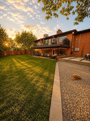 Une maison moderne dotée d’un grand jardin, d’un patio couvert et d’une pelouse bien entretenue.