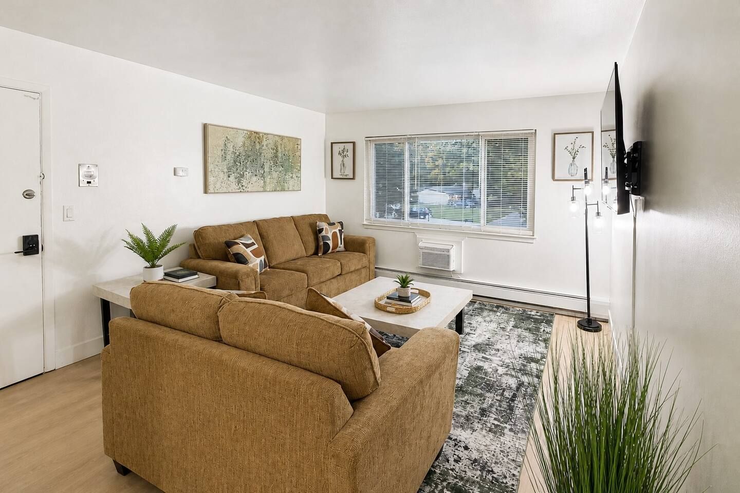 A living room with a sofa set, a coffee table, a floor lamp, and a large window with blinds.