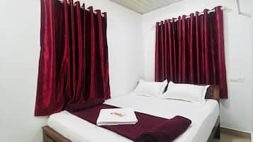 A single bed with a wooden headboard, white bedding, and a red throw blanket.