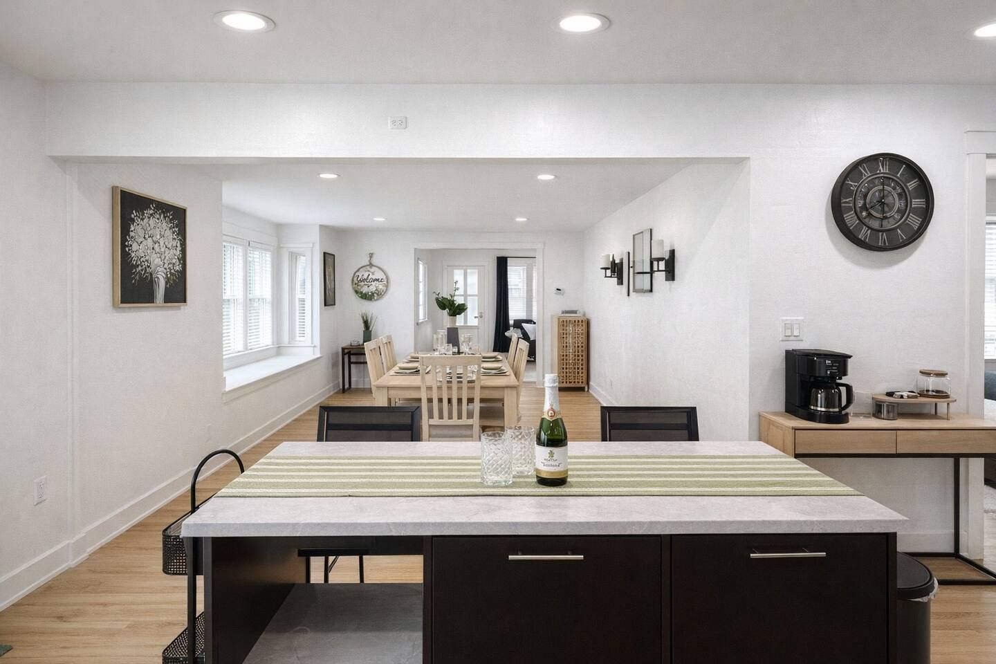 Una cocina moderna con una isla central, un comedor con mesa y sillas, y una estación de café.