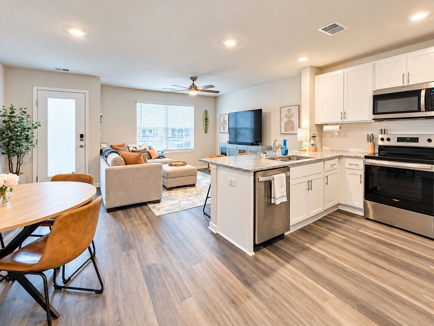 A modern kitchen with white cabinets, stainless steel appliances, and a dining area with a wooden table and chairs.