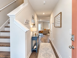 Un couloir avec un escalier, un coin repas et une porte équipée d’un dispositif de sécurité.