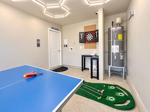 Une pièce équipée d’une table de ping-pong, d’un jeu de fléchettes et d’un chauffe-eau.