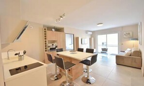 A modern kitchen with a dining area, a sofa, and a staircase. - IDEALLY LOCATED JUST A TWO-MINUTE WALK FROM THE ICONIC CROISETTE (Cannes)