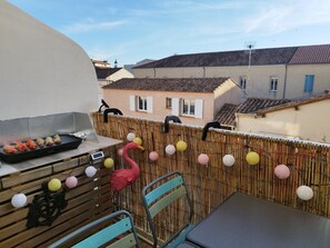 A balcony with a grill, chairs, and a decorative flamingo. - New Listing (Le Grau-du-Roi)