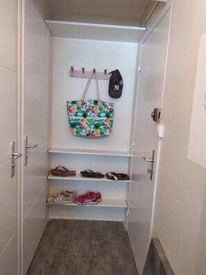 Ein Flur mit Schuhablage, einer aufhängbaren Tasche und einer Mütze an der Wand.