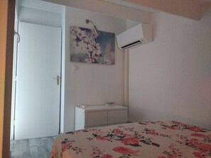 A bedroom with a bed, a white dresser, a painting, and an air conditioning unit. - New Listing (Le Grau-du-Roi)