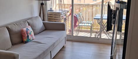 A living room with a sofa, a lamp, and a view of the outside balcony.