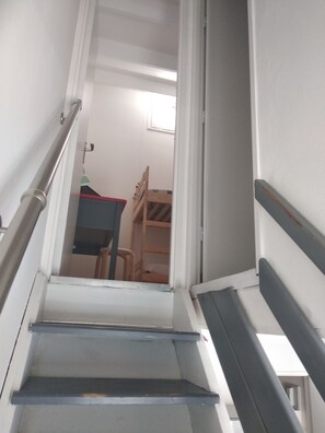 Eine Treppe führt zu einem Raum mit Etagenbetten und einem Schreibtisch.