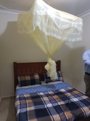 Une chambre à coucher avec un lit, un baldaquin et une personne debout près du lit.