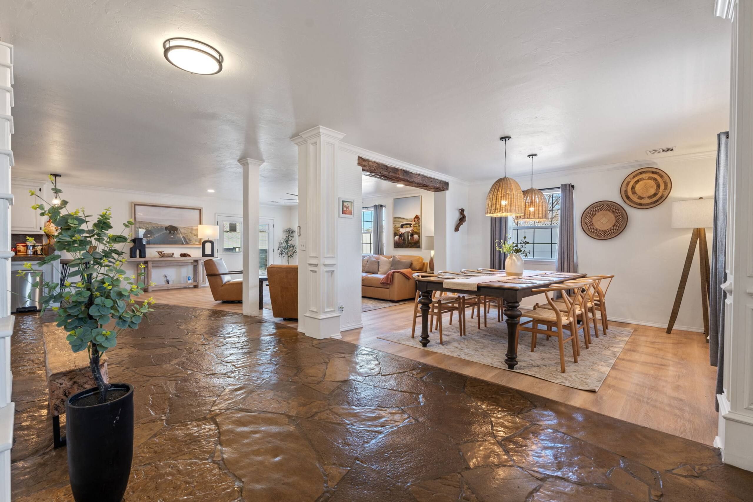 A spacious living area with a stone floor, a dining table with chairs, and a kitchen in the background.