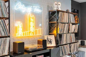 A room with a vinyl record collection, a neon sign, and a speaker. - City of Trees House with Hot Tub & Game Room (West Sacramento)