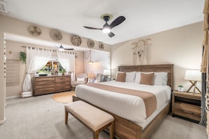 A bedroom with a large bed, a wooden nightstand, a desk, a ceiling fan, and a window with curtains. - City of Trees House with Hot Tub & Game Room (West Sacramento)