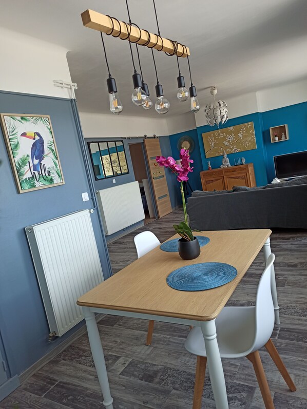 A modern living room with a dining table, chairs, a sofa, and a TV. - New Listing (Dunkerque)