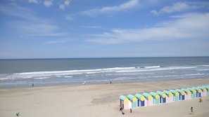 Ein Strand mit einer Reihe bunter Strandhäuser und dem Meer im Hintergrund.