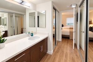 A modern bathroom with a large mirror, a sink, and a potted orchid. - Blue Marina' Marina And Pool View Top Floor Pool, Gym, Jacuzzi (Marina del Rey)