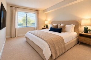 A bedroom with a large bed, two bedside tables with lamps, a window with curtains, and a flat-screen TV mounted on the wall. - Blue Marina' Marina And Pool View Top Floor Pool, Gym, Jacuzzi (Marina del Rey)