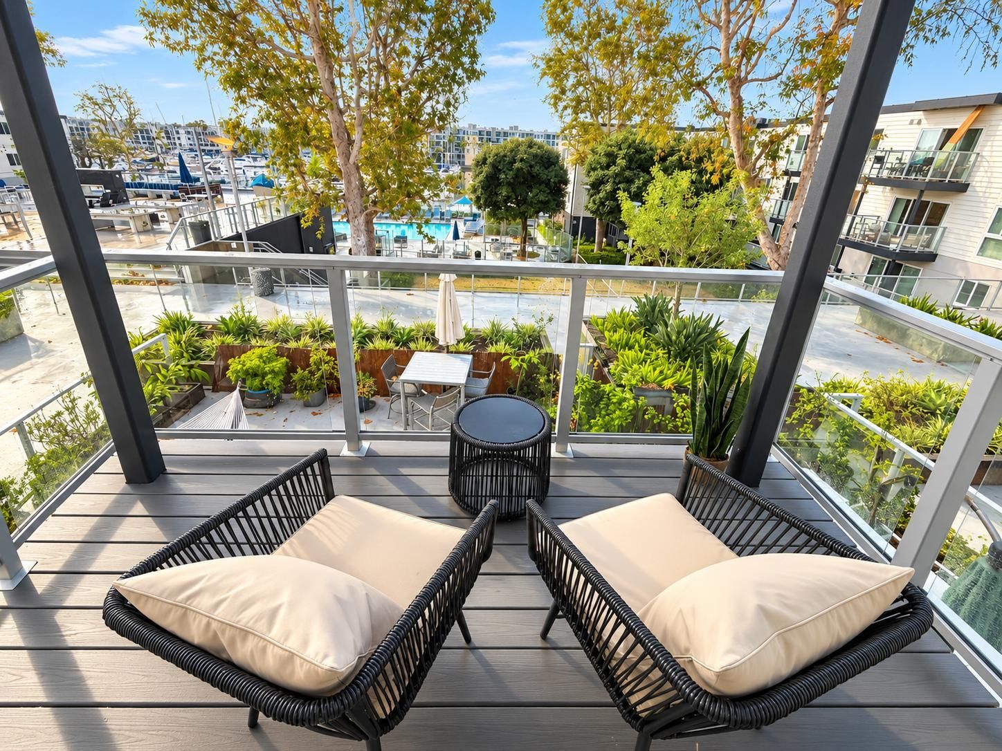 Ein Balkon mit Korbmöbeln, einem Tisch und Topfpflanzen.