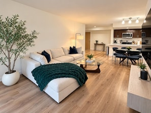 Een moderne woonkamer met een bank, salontafel en een potplant.