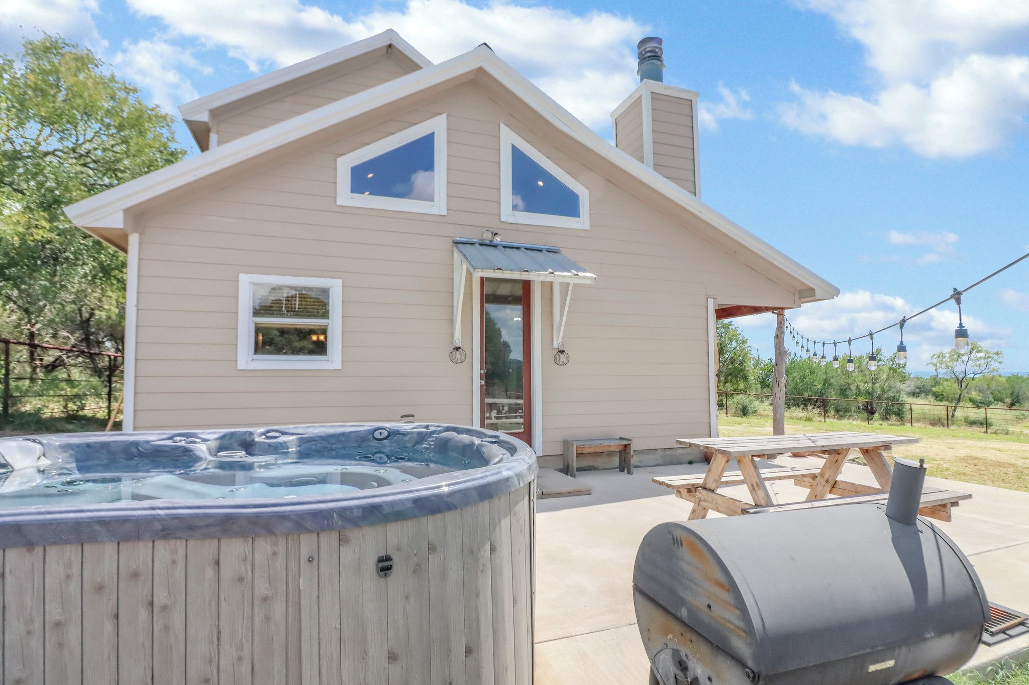 Une maison à deux étages dotée d’un jacuzzi, d’un barbecue et d’une table de pique-nique.