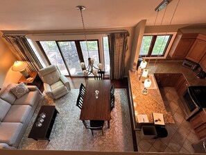 Een moderne woonkamer met een bank, een eettafel en een keuken met granieten aanrechtbladen.